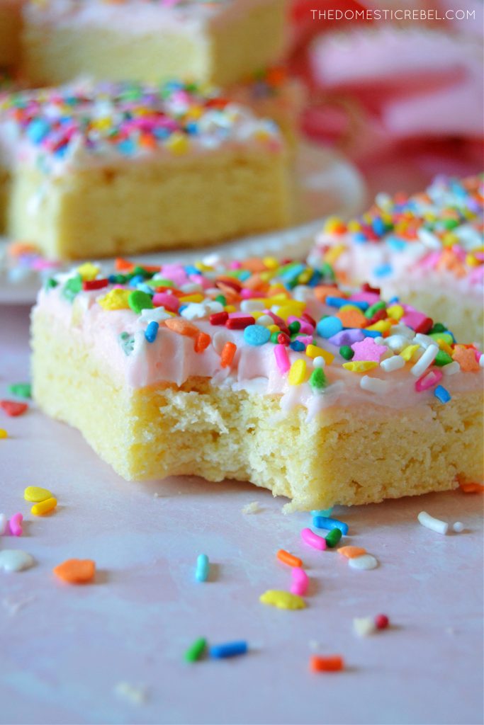 Sugar Cookie Bars with a bite missing on a pink board
