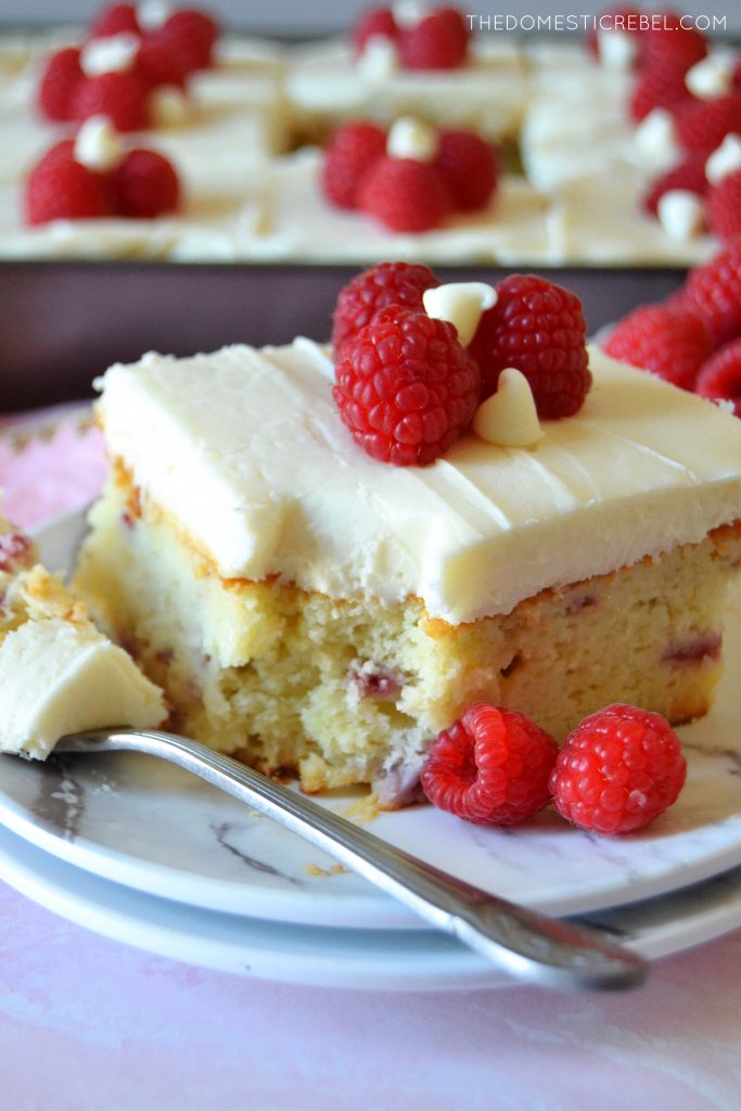 slice of white choc raspberry cake with a bite missing on a white plate