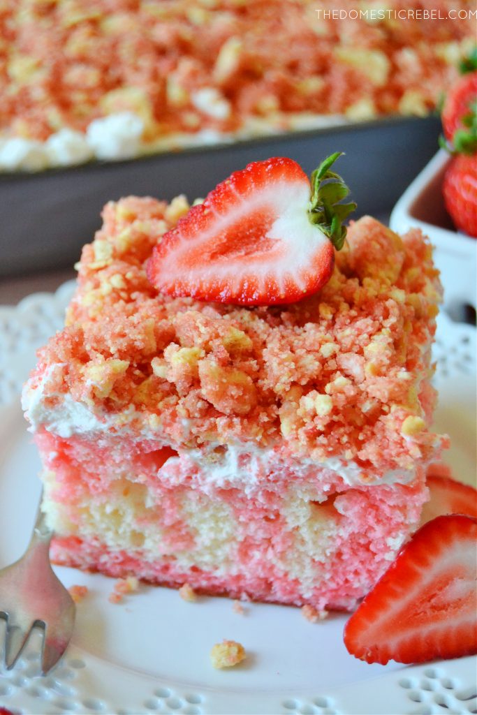 a closeup square slice of strawberry crunch poke cake on a white plate