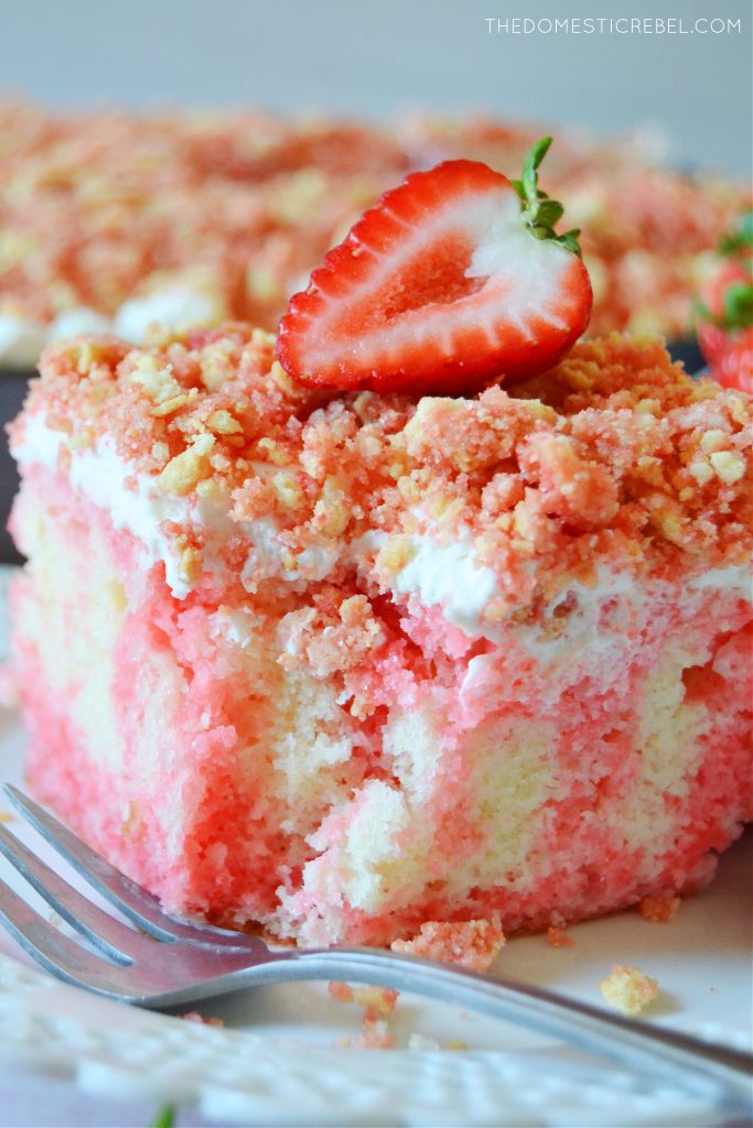closeup of a slice of strawberry crunch poke cake with a bite missing
