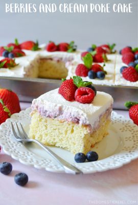 square piece of berries and cream poke cake on a white plate