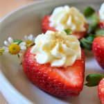 cheesecake stuffed strawberry with a daisy on a white plate