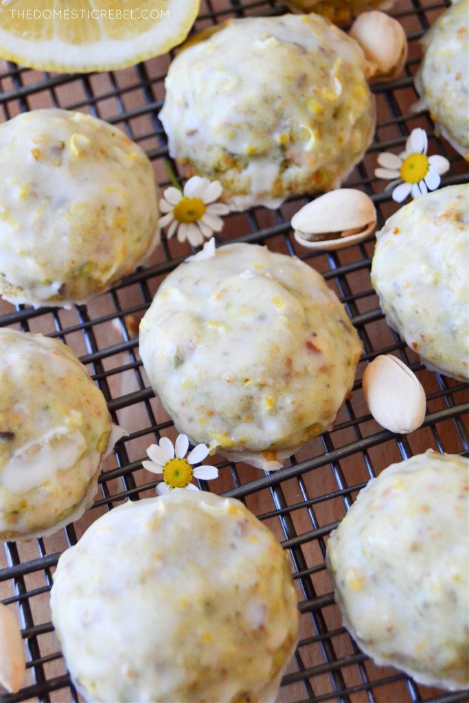 closeup of pistachio lemon cookies on a wire rack with pistachio nuts and daisies