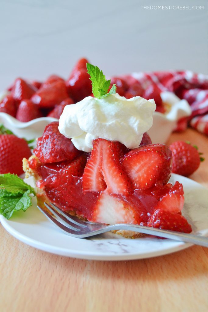 a side profile slice of strawberry pie on a white plate with a fork