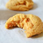 a brown butter pumpkin spice cookie with a bite missing on parchment paper