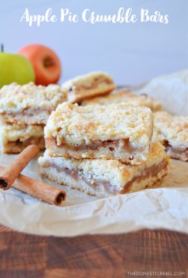 two apple crumble bars stacked on parchment paper with cinnamon sticks