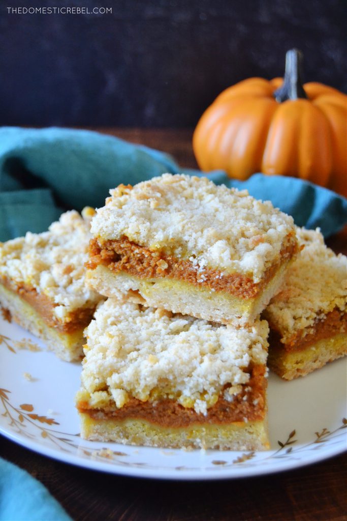 a plateful of pumpkin pie crumble bars with a pumpkin in the background