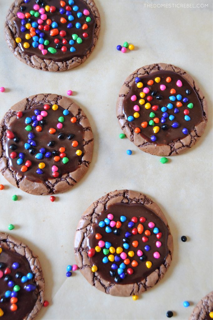 an arrangement of cosmic brownie cookies on parchment with a scattering of sprinkles