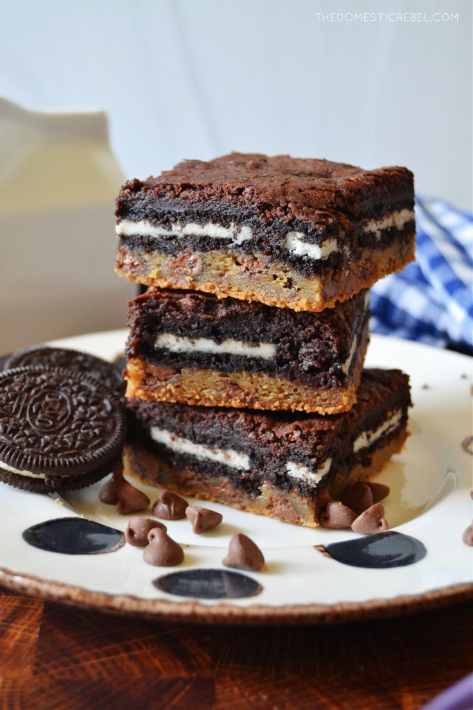 a triple stack of slutty brownies on a white polka dot plate
