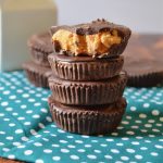 homemade peanut butter cups stacked up 4 high on a teal tea towel