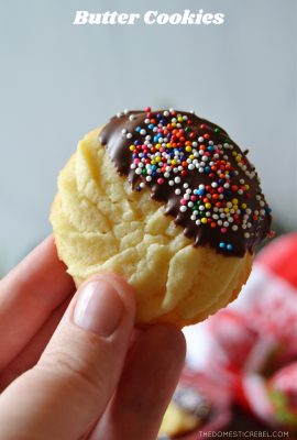 author holding a butter cookie dipped in milk chocolate and sprinkles