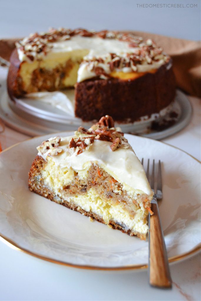 carrot cake cheesecake slice on a white plate with a wooden fork