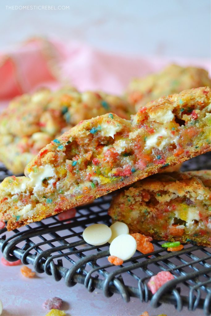 a split open fruity pebble cookie on a wire rack with white chocolate chips