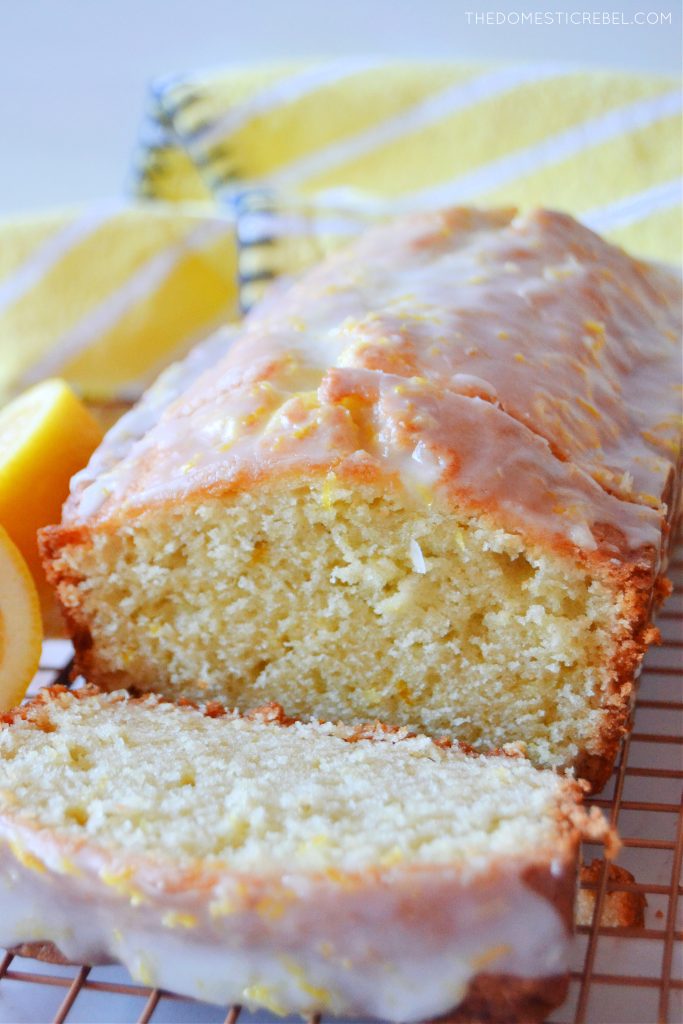 lemon loaf cake with a slice cut off and a yellow cloth in the background