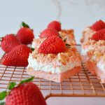 rows of strawberry shortcake bars on a wire rack with fresh strawberries on the side
