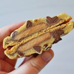 the author is holding a split open PB cup stuffed chocolate chip cookie to show the inside of the cookie