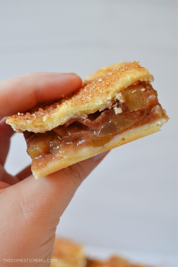 author holding an apple pie bar piece to show texture and interior of the apple pie bar
