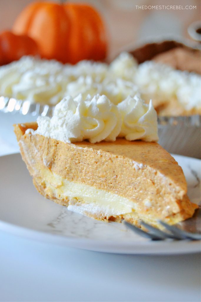 a closeup side shot of a slice of pumpkin pie cheesecake on a white plate with a fork