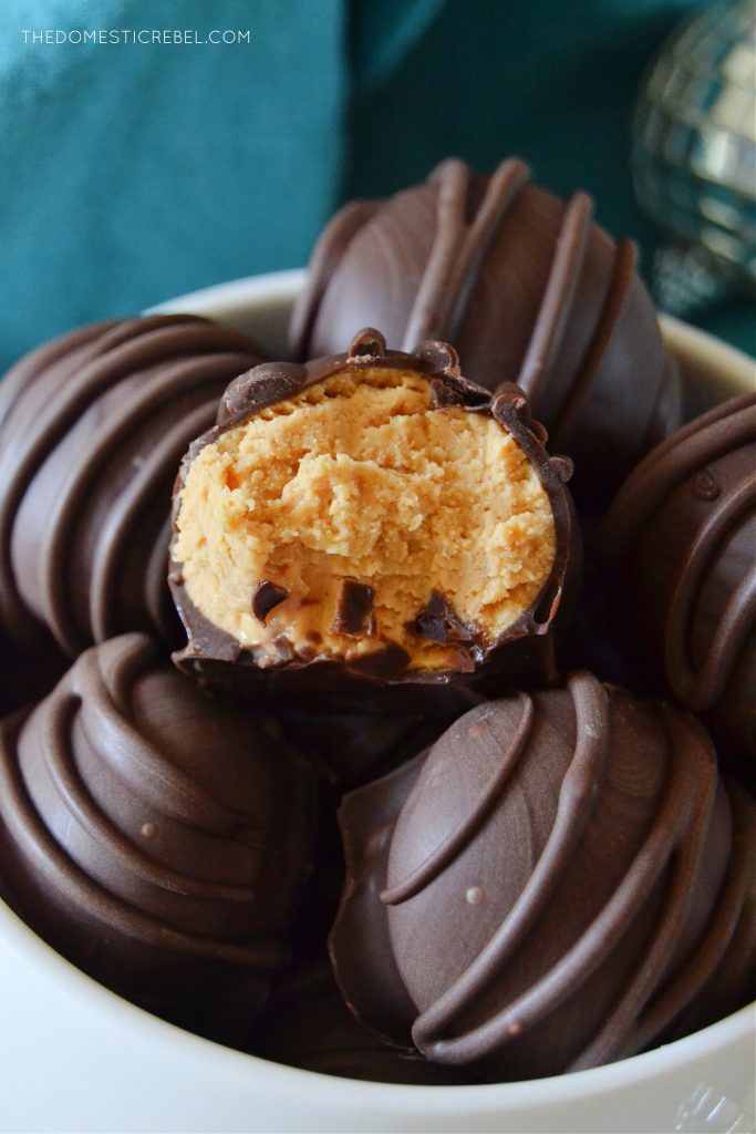 closeup of a bowl full of peanut butter balls. one has a bite missing from it.