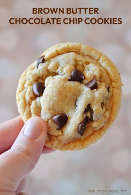 Photographer is holding a brown butter chocolate chip cookie against a light colored background.