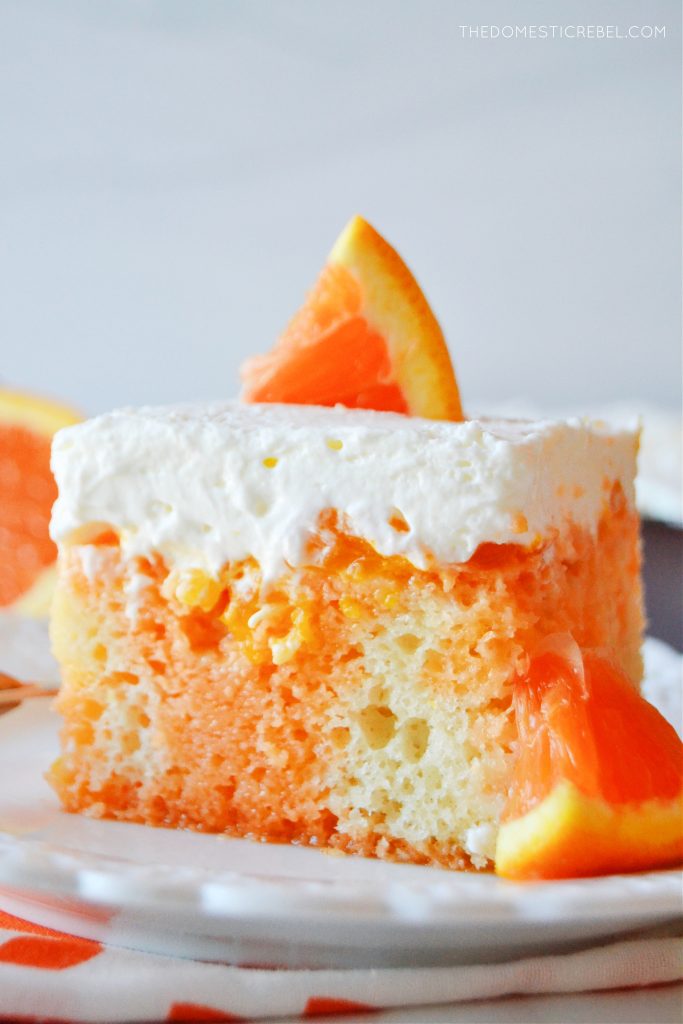 an extreme closeup shot of a square piece of orange creamsicle poke cake on a scalloped white plate.