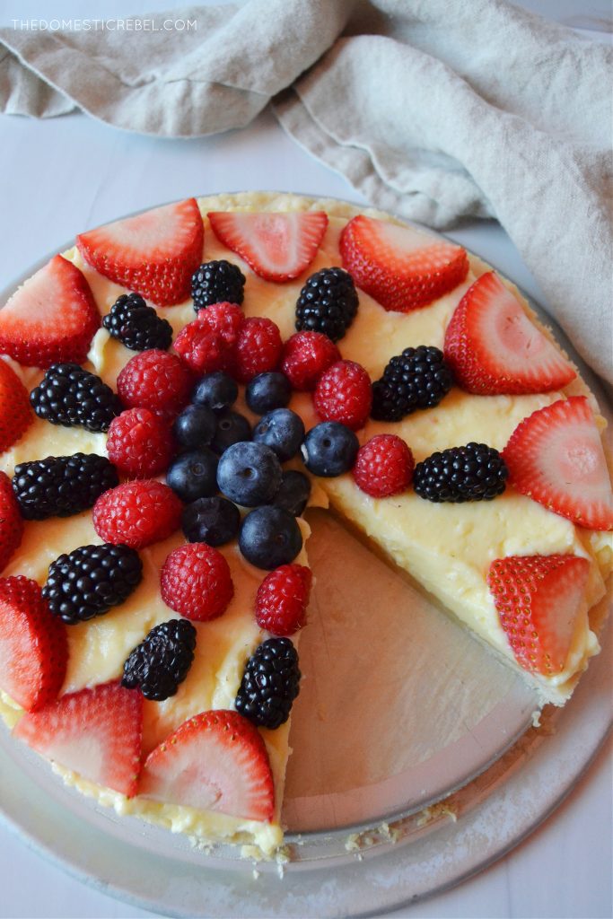 an aerial shot of a homemade fruit tart on a white board with a linen napkin next to it.