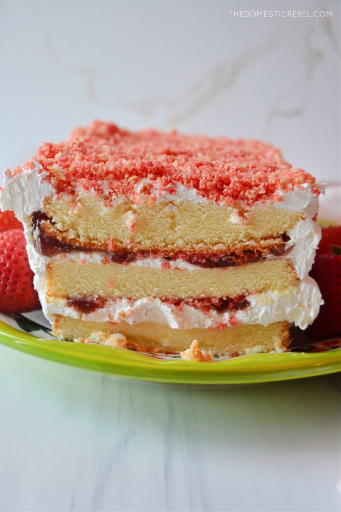 a close-up of the strawberry shortcake icebox cake on a green plate with strawberries next to it.