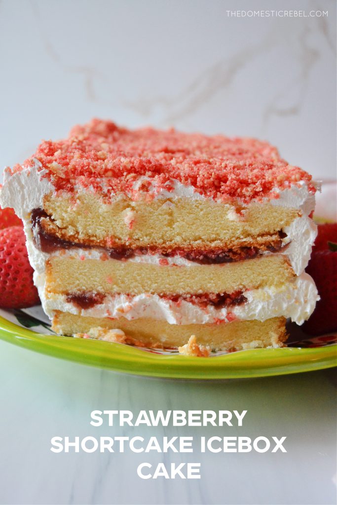 strawberry shortcake icebox cake on a green platter with fresh strawberries sitting around it.