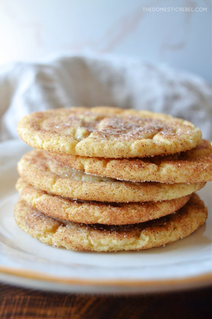 a five-high stack of brown butter snickerdoodles on a white plate. a linen cloth is rumpled in the background.