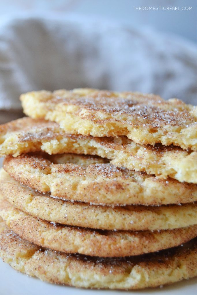 a stack of brown butter snickerdoodle cookies. the top cookie has been split in half to show the inside of the cookie's texture.