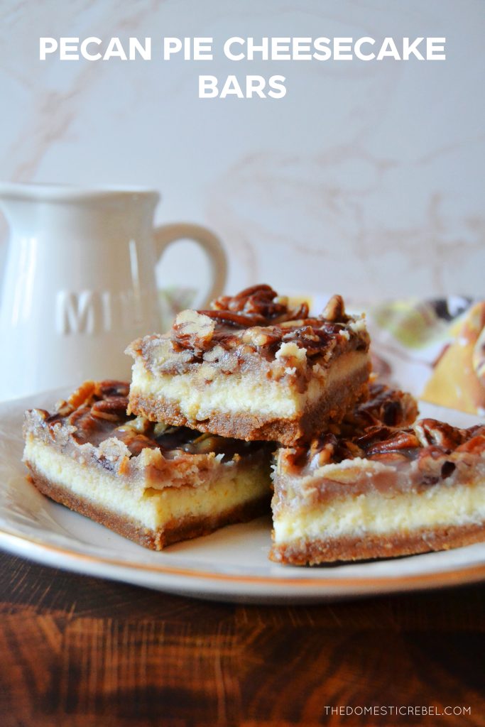 a trio stack of pecan pie cheesecake bars arranged on a gold-rimmed white plate. a milk jug and floral fall-themed dish towel are in the background.