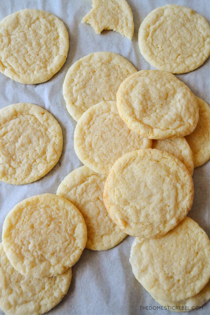 sugar cookies scattered haphazardly on a parchment-lined baking sheet. 