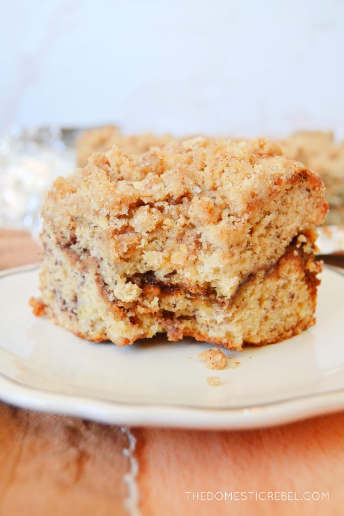 a piece of banana bread coffee cake sitting on a white plate. a bite has been taken out of the coffee cake.